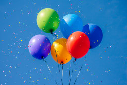 Colorful Balloons and Confetti Against Blue Sky