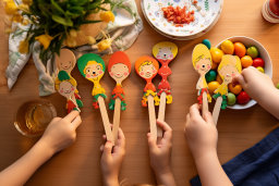 a group of hands holding wooden spoons with faces on them