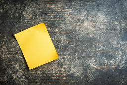 Yellow Sticky Note on Textured Wood Background