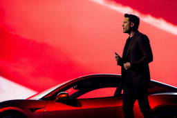 Un homme debout à côté d'une voiture rouge