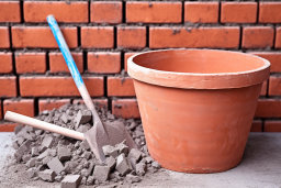 a clay pot and shovel next to a brick wall